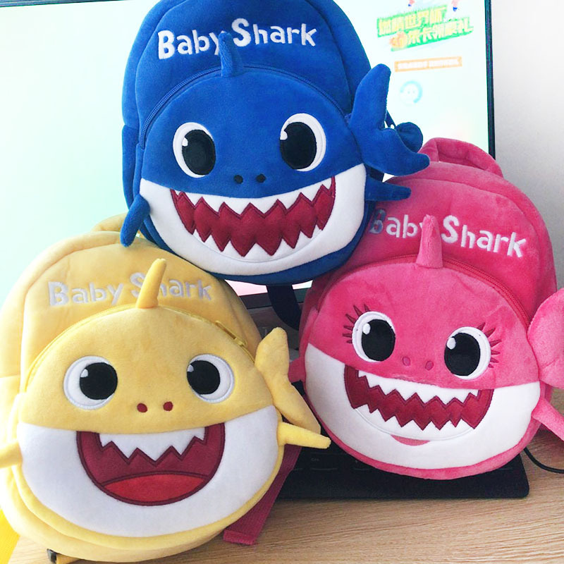 3 sacs à dos en peluche pour enfant représentant un requin mignon. Celui-ci est posé sur une table à plat